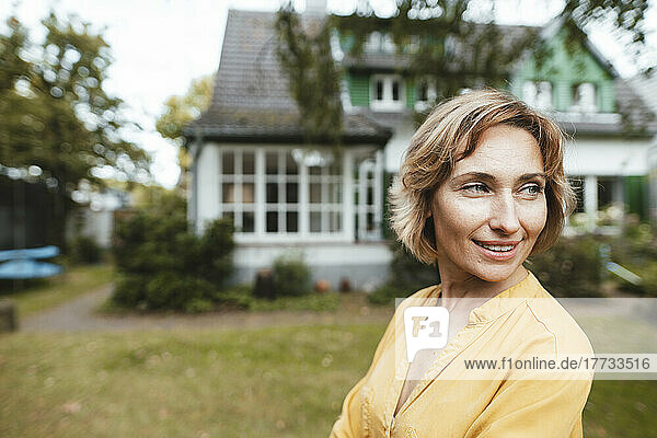Happy woman standing in front of house