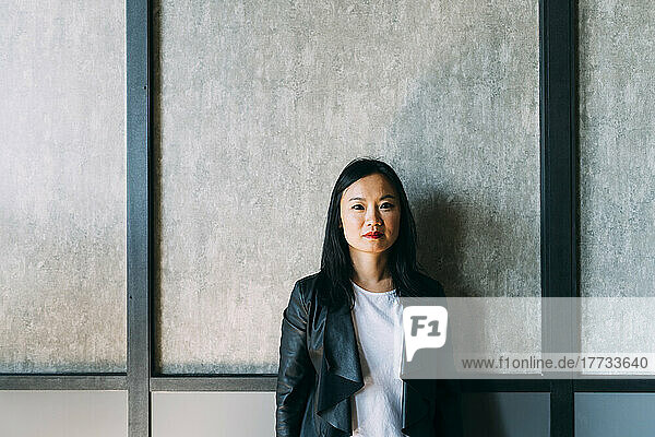 Confident businesswoman in front of wall at office