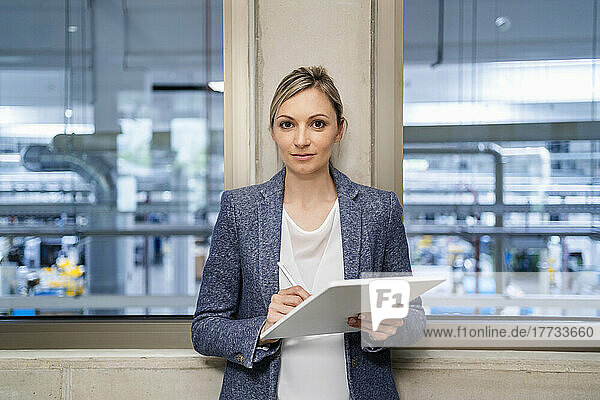 Portrait of businesswoman holding digital tablet in factory office