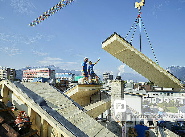 Workers standing on rooftop at construction site on sunny day