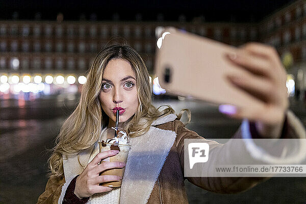 Young woman taking selfie on smart phone in city