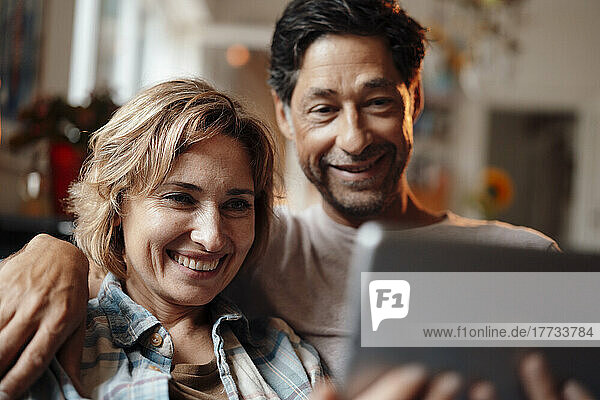 Happy woman sharing tablet PC with man at home
