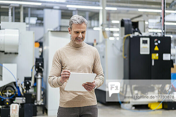 Mature businessman using digital tablet in factory