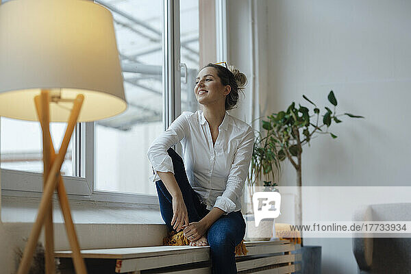 Happy woman sitting on widow sill at home