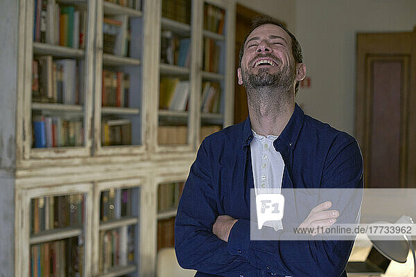 Freelancer with arms crossed laughing at home office