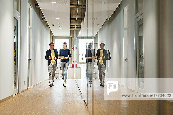 Businessman and businesswoman walking on office floor