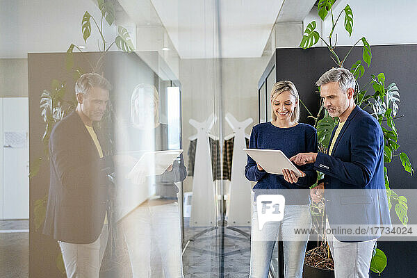 Businessman and businesswoman sharing digital tablet in office