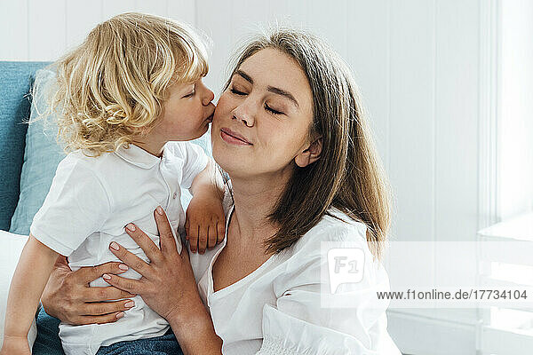 Netter Junge küsst Mutter zu Hause auf die Wange