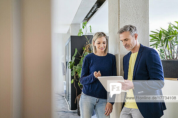 Businessman and businesswoman working together on digital tablet in office