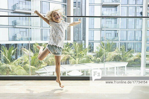 Fröhliches Mädchen springt auf Balkon