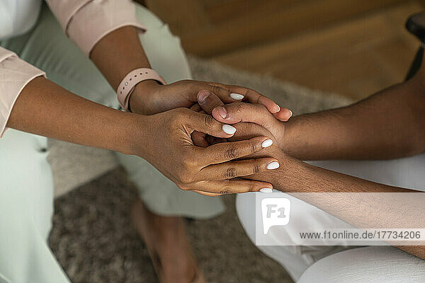 Psychologist holding hands of patient and consoling at office