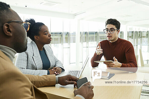 Businessman wearing eyeglasses discussing strategy with colleagues in meeting