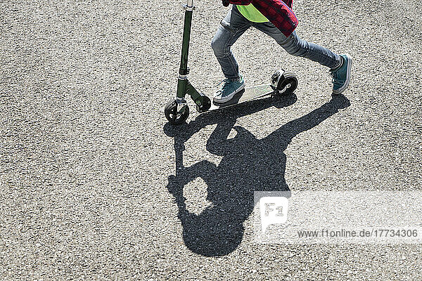 Boy riding push scooter on road