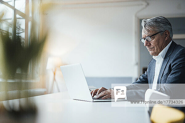 Senior businessman working on laptop at desk