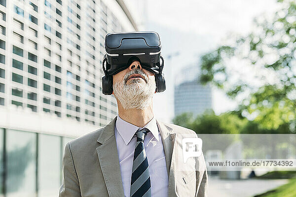 Geschäftsmann mit Virtual-Reality-Simulator steht vor dem Gebäude
