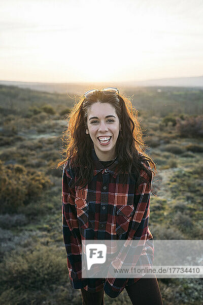 Happy woman in plaid shirt at sunset