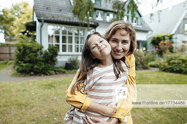 Happy girl with mother standing in front of house