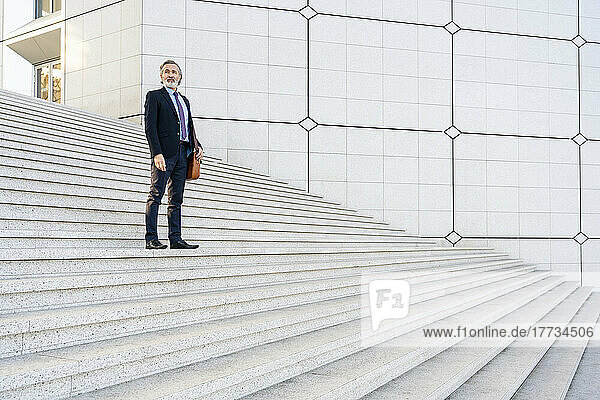 Mature businessman standing on staircase
