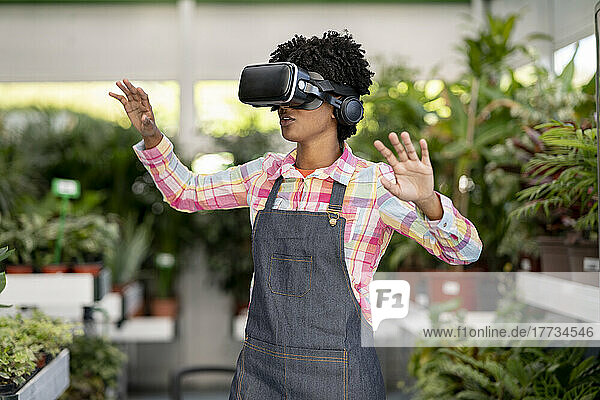 Gardener wearing virtual reality headset gesturing at plant nursery