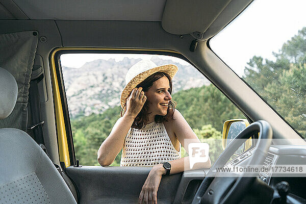 Glückliche junge Frau mit der Hand im Haar  gesehen durch das Van-Fenster