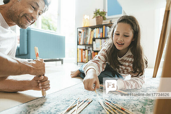 Smiling father and daughter playing mikado at home