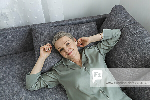 Smiling mature woman lying on couch in living room
