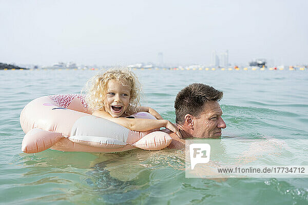 Happy girl with father swimming in sea