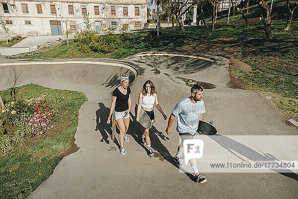 Man and women holding skateboards walking on sports ramp
