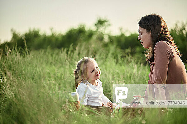 Daughter talking to mother on picnic in agricultural field