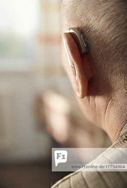Senior man wearing hearing aid at home