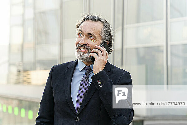 Smiling mature businessman with gray hair talking on smart phone