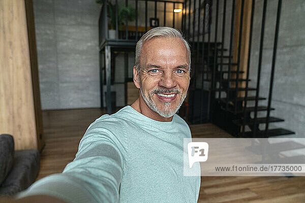 Smiling man taking selfie at home