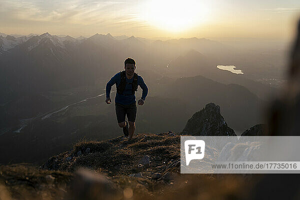 Mann rennt bei Sonnenuntergang auf den Sauling-Berg