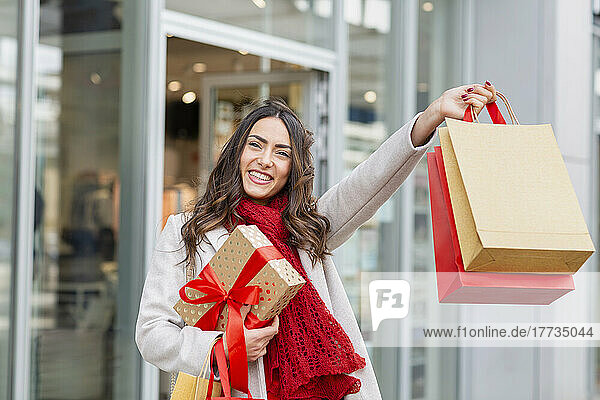 Happy young woman holding shopping bags with Christmas present
