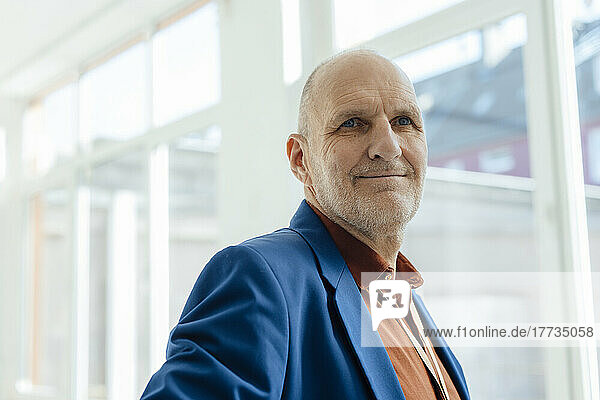 Smiling senior businessman wearing blue blazer in office