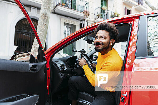 Smiling Afro man disembarking from car