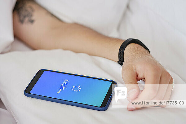 Hands of man by mobile phone showing alarm on smart phone