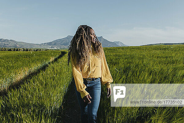 Young woman walking in meadow on sunny day