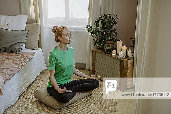 Woman sitting cross-legged practicing breathing exercise at home