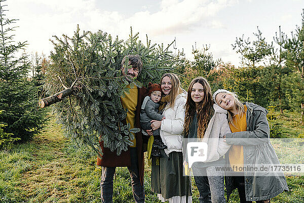 Happy family standing together at Christmas tree farm
