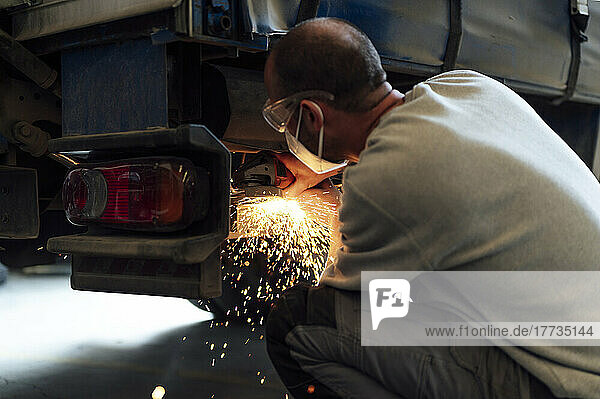 Auto expert cutting metal of car in workshop