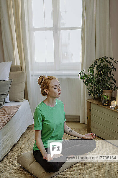 Woman with eyes closed meditating at home