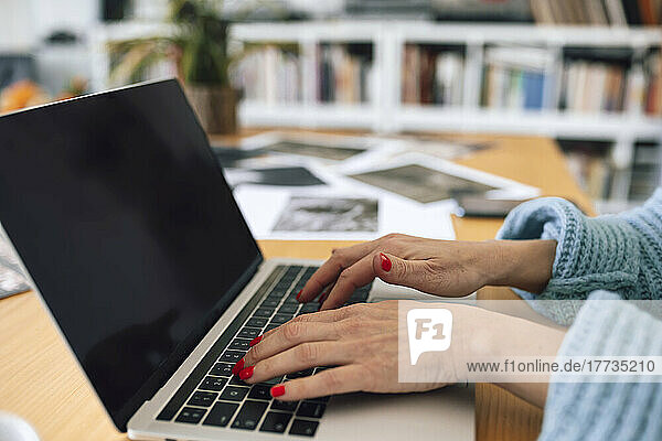 Hands of businesswoman typing on laptop at home