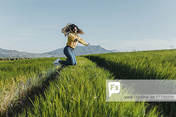 Smiling young woman jumping on green grass