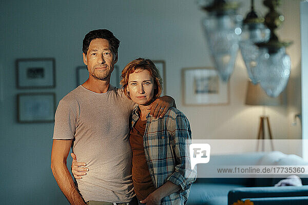 Mature man and woman standing together in living room at home