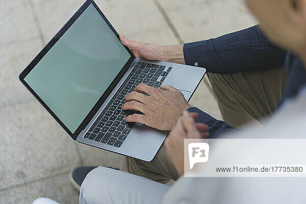 Hand of businessman using laptop by businesswoman