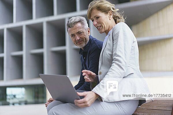 Businesswoman discussing over laptop with businessman