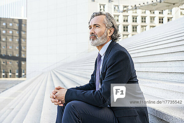 Businessman with gray hair and beard sitting on steps