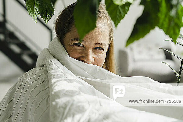 Woman wrapped in white blanket at home