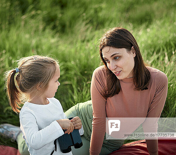 Mother and daughter talking on picnic in field